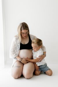 Broertje hand op de buik tijdens zwangerschapsshoot